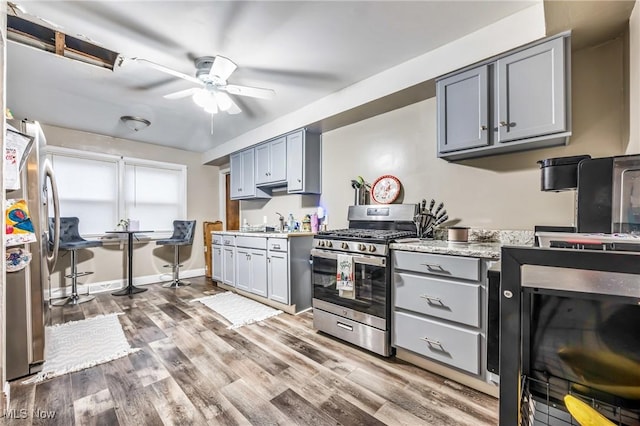 kitchen with gray cabinetry, ceiling fan, hardwood / wood-style floors, and appliances with stainless steel finishes