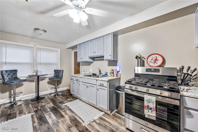 kitchen with gas stove, gray cabinets, sink, and dark hardwood / wood-style floors