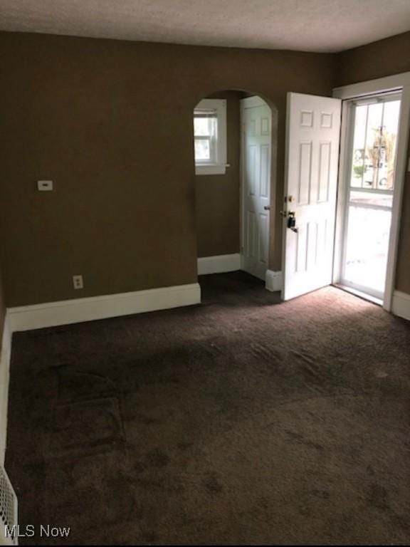 spare room featuring a textured ceiling and dark colored carpet