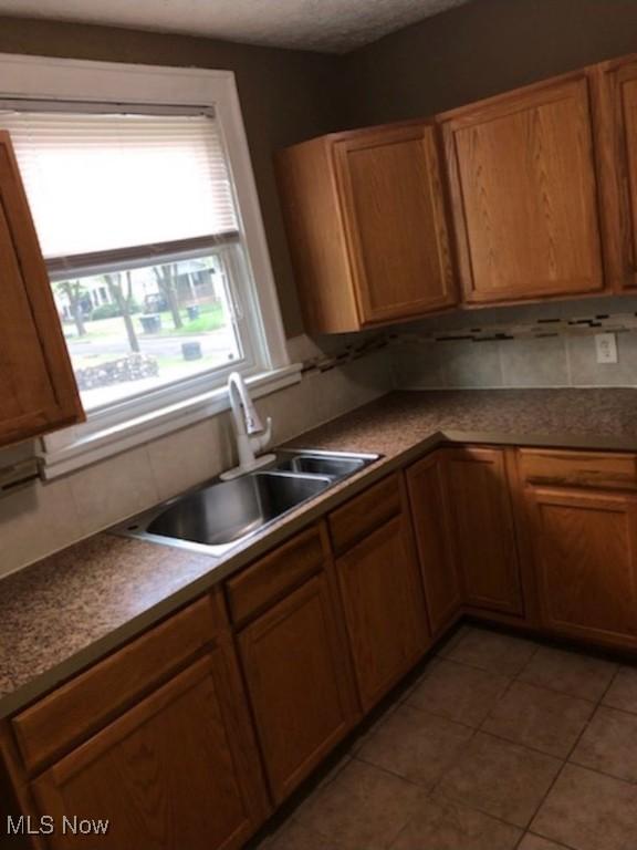 kitchen featuring decorative backsplash, sink, and light tile patterned flooring