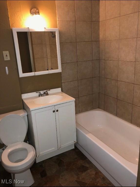 full bathroom with vanity, tiled shower / bath combo, and toilet