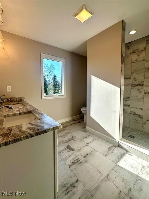 bathroom with tiled shower, vanity, and toilet