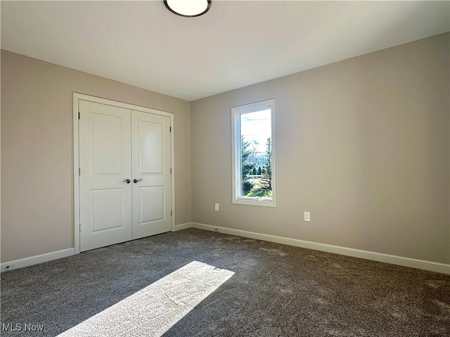 unfurnished bedroom featuring dark carpet and a closet