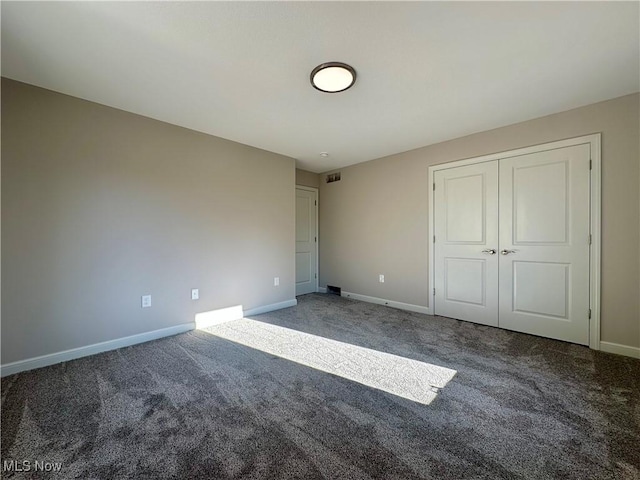 unfurnished bedroom with dark carpet and a closet