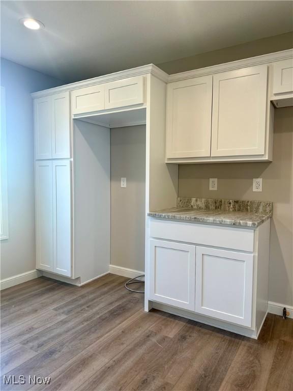 kitchen featuring white cabinetry, light hardwood / wood-style floors, and light stone counters