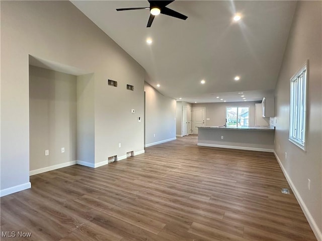 unfurnished living room with ceiling fan, high vaulted ceiling, and wood-type flooring