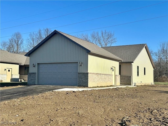 view of front facade with a garage, roof with shingles, aphalt driveway, and brick siding