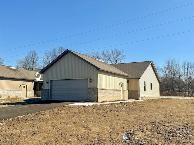 view of front of property featuring driveway, brick siding, and an attached garage