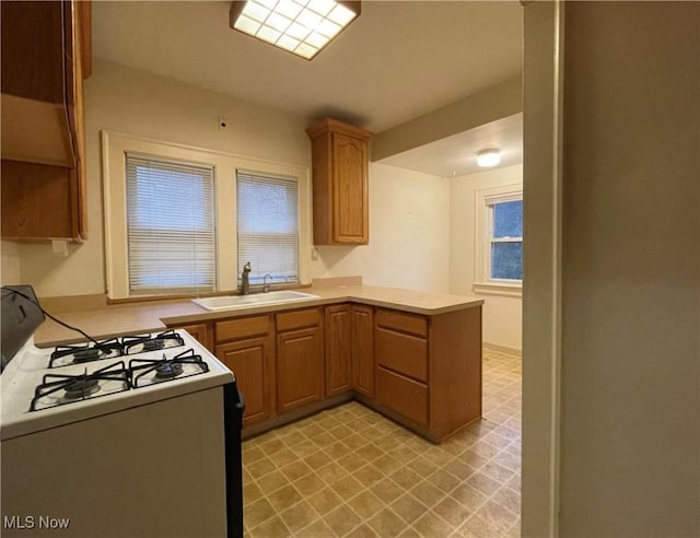 kitchen featuring kitchen peninsula, sink, and white range with gas cooktop