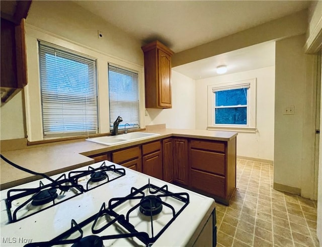 kitchen featuring kitchen peninsula, white cooktop, and sink