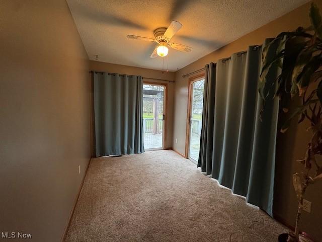 carpeted spare room featuring ceiling fan and a textured ceiling