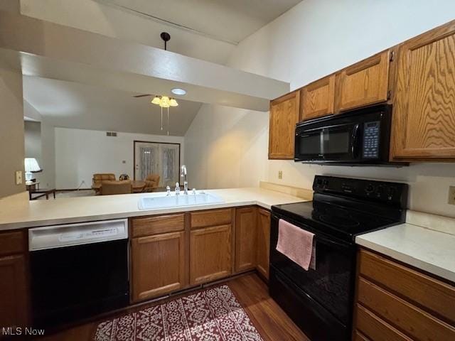 kitchen with black appliances, kitchen peninsula, sink, and vaulted ceiling