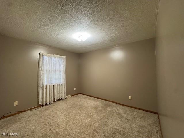 carpeted empty room with a textured ceiling