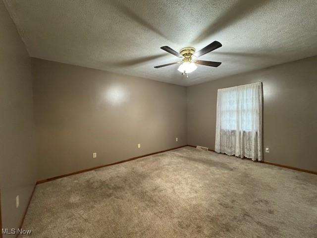 carpeted spare room with ceiling fan and a textured ceiling