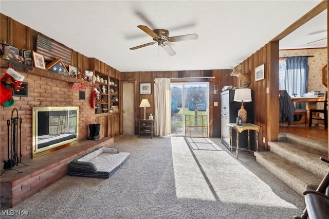 carpeted living room featuring wood walls and ceiling fan