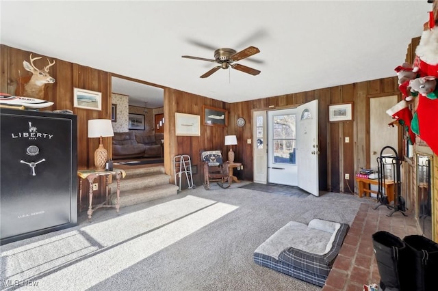 interior space featuring dark colored carpet, ceiling fan, and wood walls