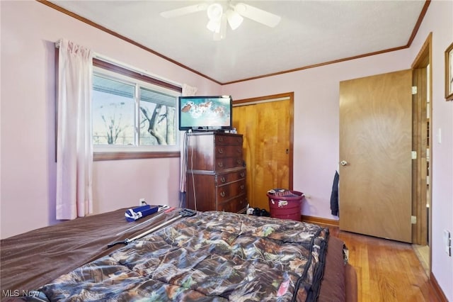 bedroom featuring ceiling fan, light wood-type flooring, crown molding, and a closet