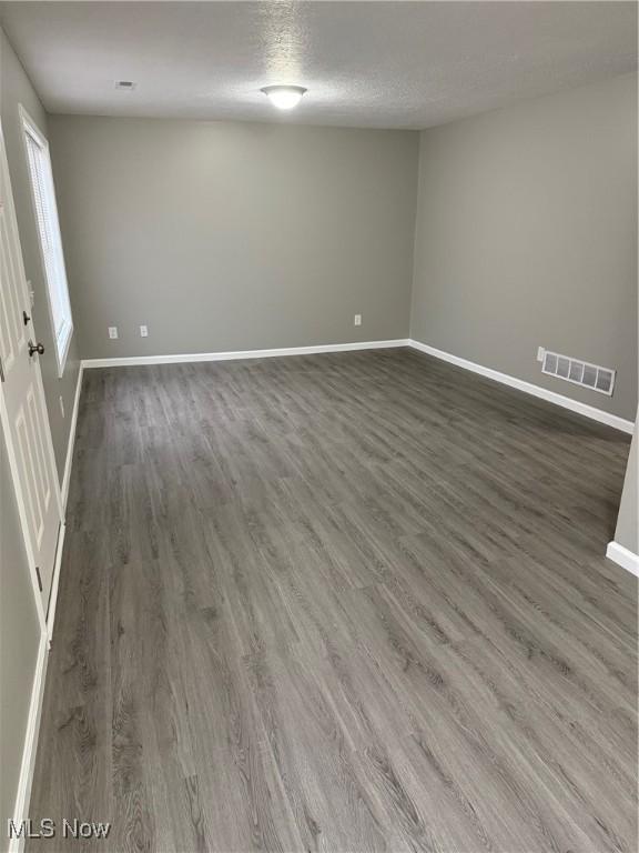 unfurnished room with dark hardwood / wood-style flooring and a textured ceiling