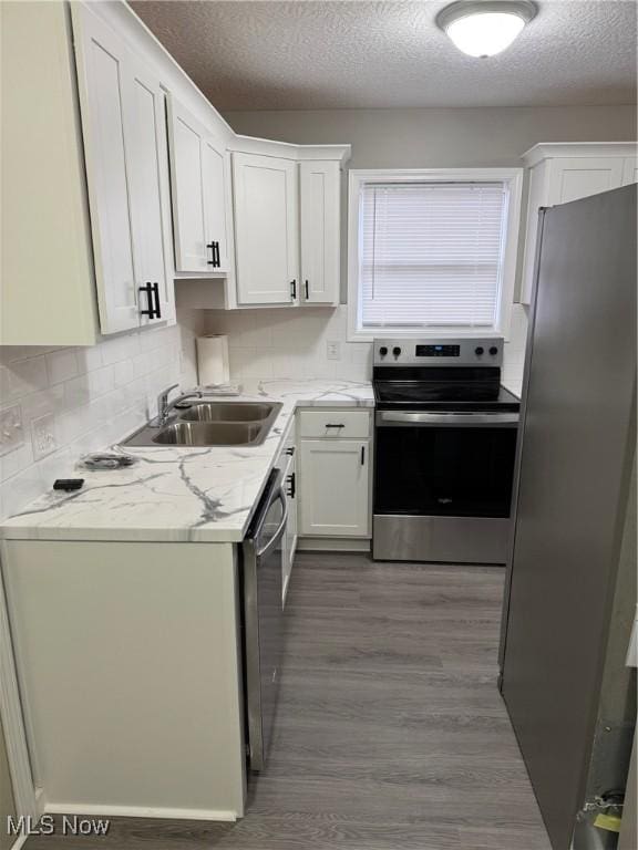 kitchen featuring hardwood / wood-style floors, white cabinets, sink, a textured ceiling, and stainless steel appliances