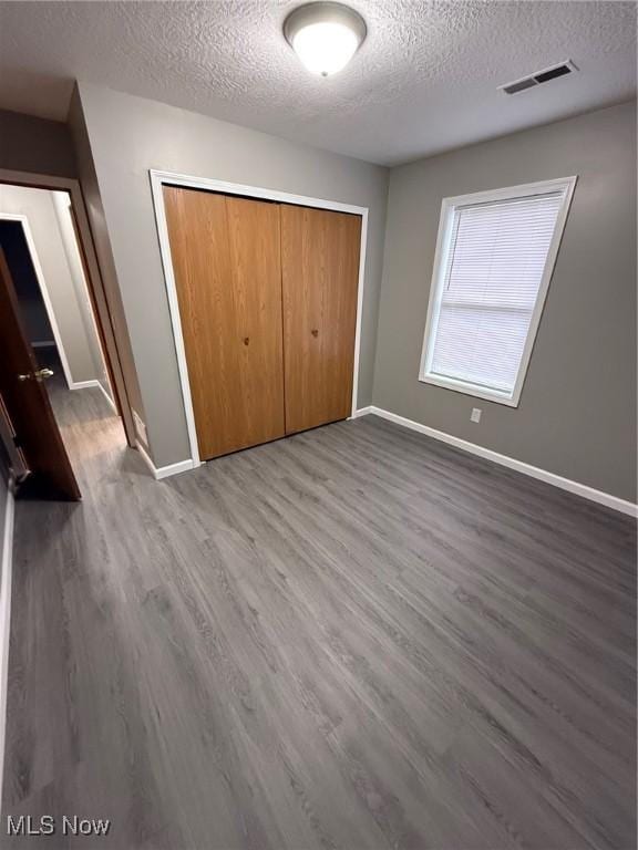 unfurnished bedroom with a closet, a textured ceiling, and hardwood / wood-style flooring