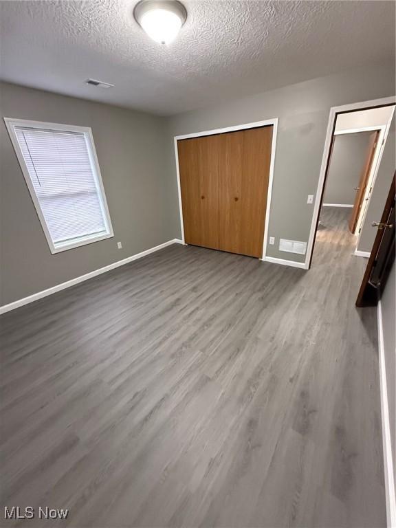 unfurnished bedroom featuring wood-type flooring, a textured ceiling, and a closet