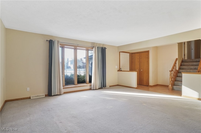 spare room featuring light colored carpet and a textured ceiling