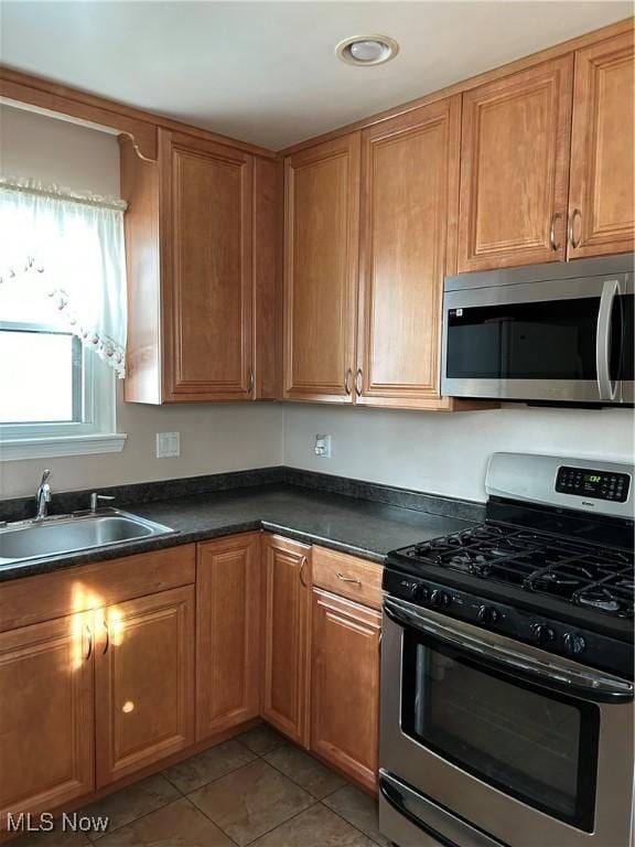 kitchen featuring stainless steel appliances, sink, and light tile patterned floors