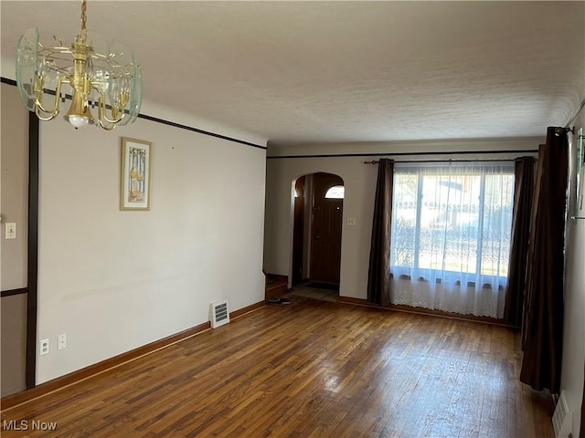 spare room featuring dark hardwood / wood-style flooring and a notable chandelier