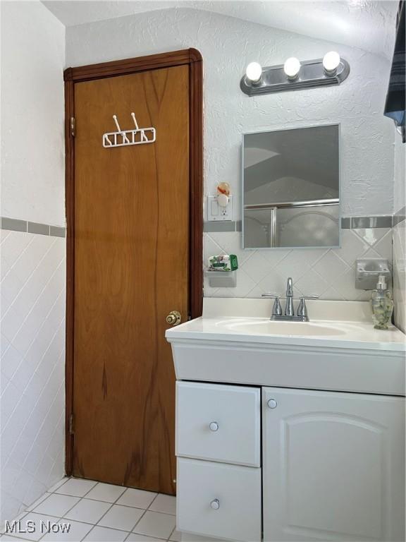 bathroom with tile walls, decorative backsplash, vanity, walk in shower, and tile patterned floors