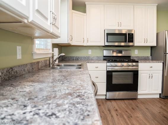 kitchen featuring white cabinetry, light hardwood / wood-style flooring, sink, and appliances with stainless steel finishes