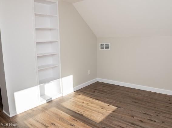 bonus room with lofted ceiling, built in features, and wood-type flooring