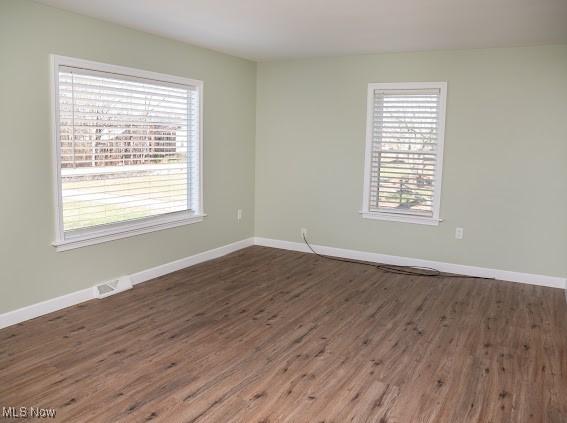 empty room with plenty of natural light and dark hardwood / wood-style floors