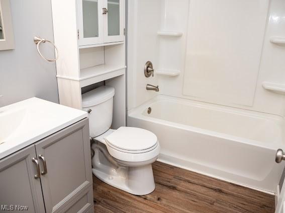 full bathroom featuring hardwood / wood-style flooring, vanity, toilet, and shower / washtub combination