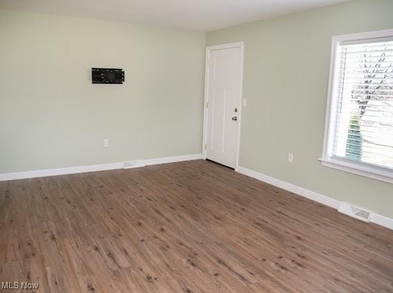 empty room with plenty of natural light and dark hardwood / wood-style flooring