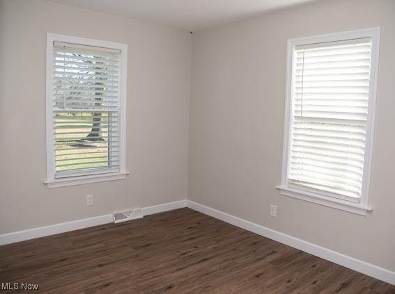 empty room with a healthy amount of sunlight and dark hardwood / wood-style flooring