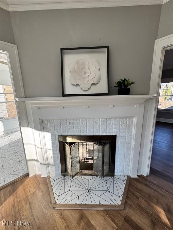 interior details featuring hardwood / wood-style floors, ornamental molding, and a tiled fireplace