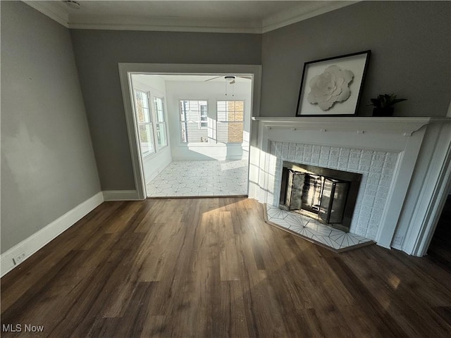 unfurnished living room featuring dark hardwood / wood-style floors, ceiling fan, crown molding, and a tiled fireplace