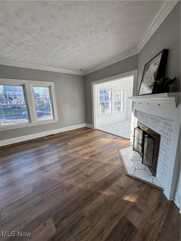 unfurnished living room featuring a tile fireplace, a textured ceiling, dark hardwood / wood-style floors, and a healthy amount of sunlight