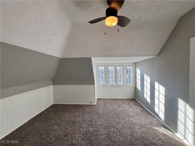 additional living space featuring ceiling fan, lofted ceiling, a textured ceiling, and carpet floors