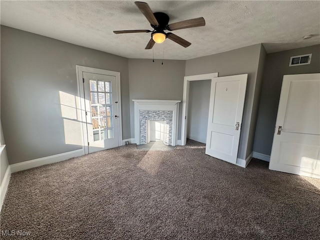 unfurnished living room featuring ceiling fan, a textured ceiling, and dark colored carpet