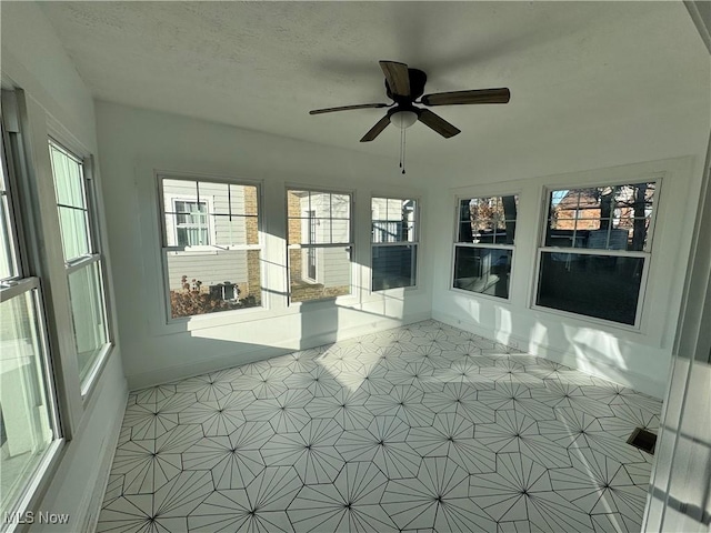 unfurnished sunroom featuring ceiling fan