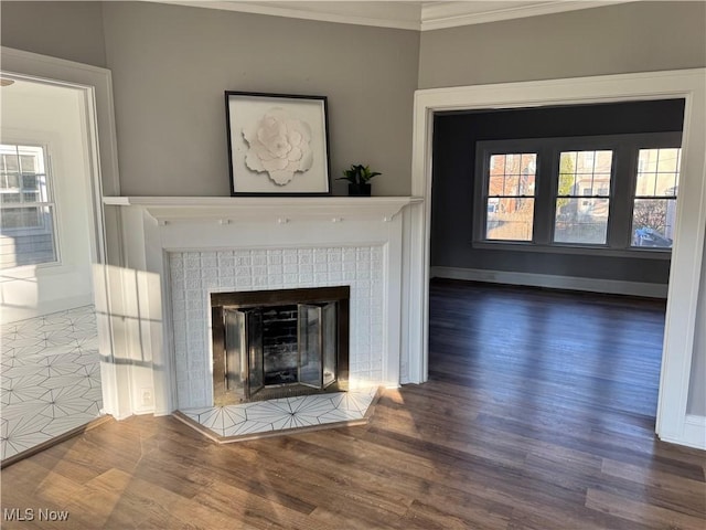 room details featuring a tiled fireplace, hardwood / wood-style floors, and ornamental molding