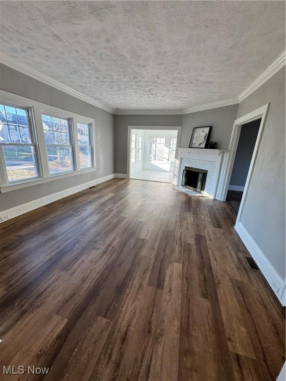 unfurnished living room with a textured ceiling, dark hardwood / wood-style flooring, and ornamental molding