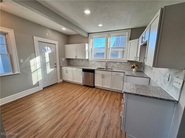 kitchen featuring tasteful backsplash, stainless steel dishwasher, stone counters, white cabinets, and light hardwood / wood-style floors