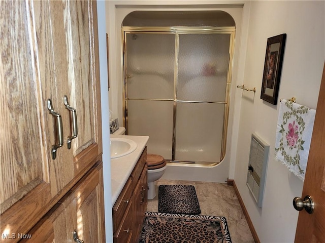 bathroom featuring heating unit, a shower with door, vanity, and toilet