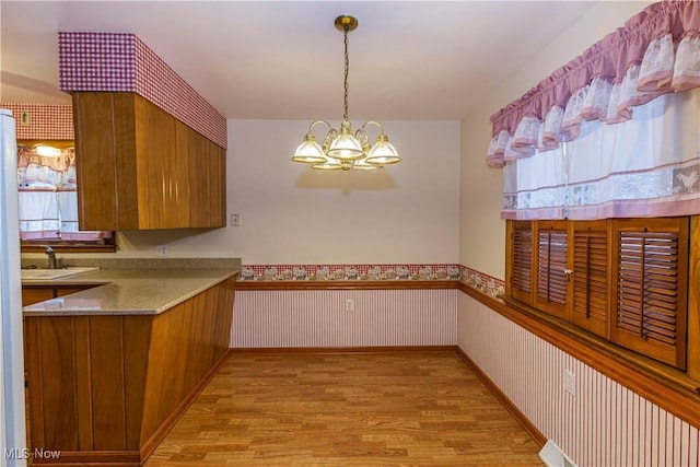 kitchen featuring a chandelier, hanging light fixtures, light hardwood / wood-style floors, and sink