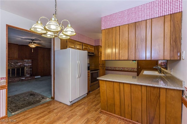 kitchen with sink, white refrigerator, kitchen peninsula, stainless steel electric range, and ceiling fan with notable chandelier