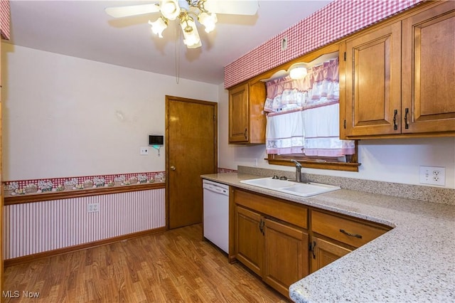 kitchen featuring light stone countertops, ceiling fan, sink, dishwasher, and light hardwood / wood-style floors