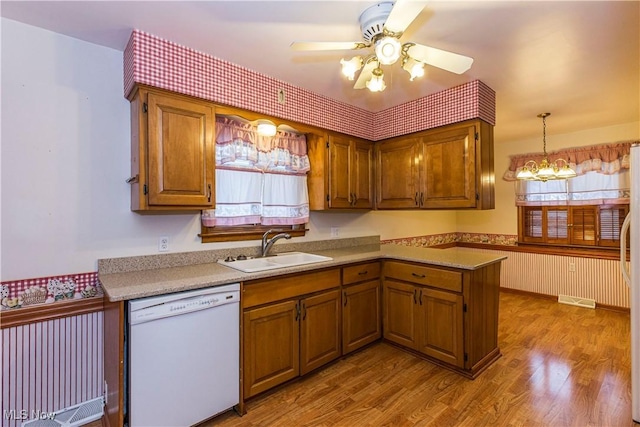 kitchen with ceiling fan with notable chandelier, white dishwasher, sink, pendant lighting, and light hardwood / wood-style floors