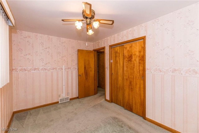 unfurnished bedroom featuring ceiling fan, light carpet, and a closet